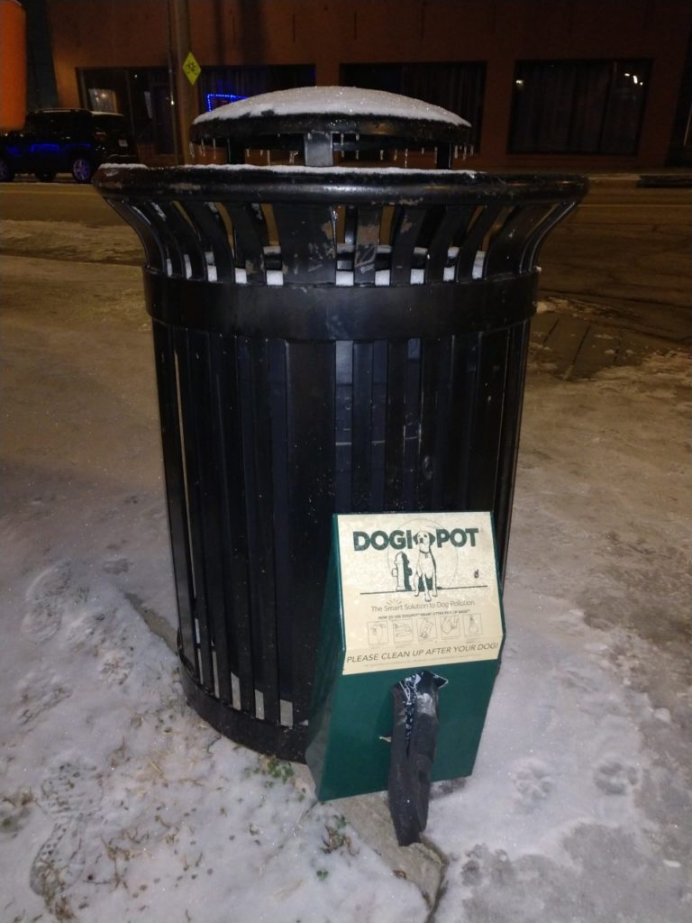 A trash can with a Dogi Pot attached to it