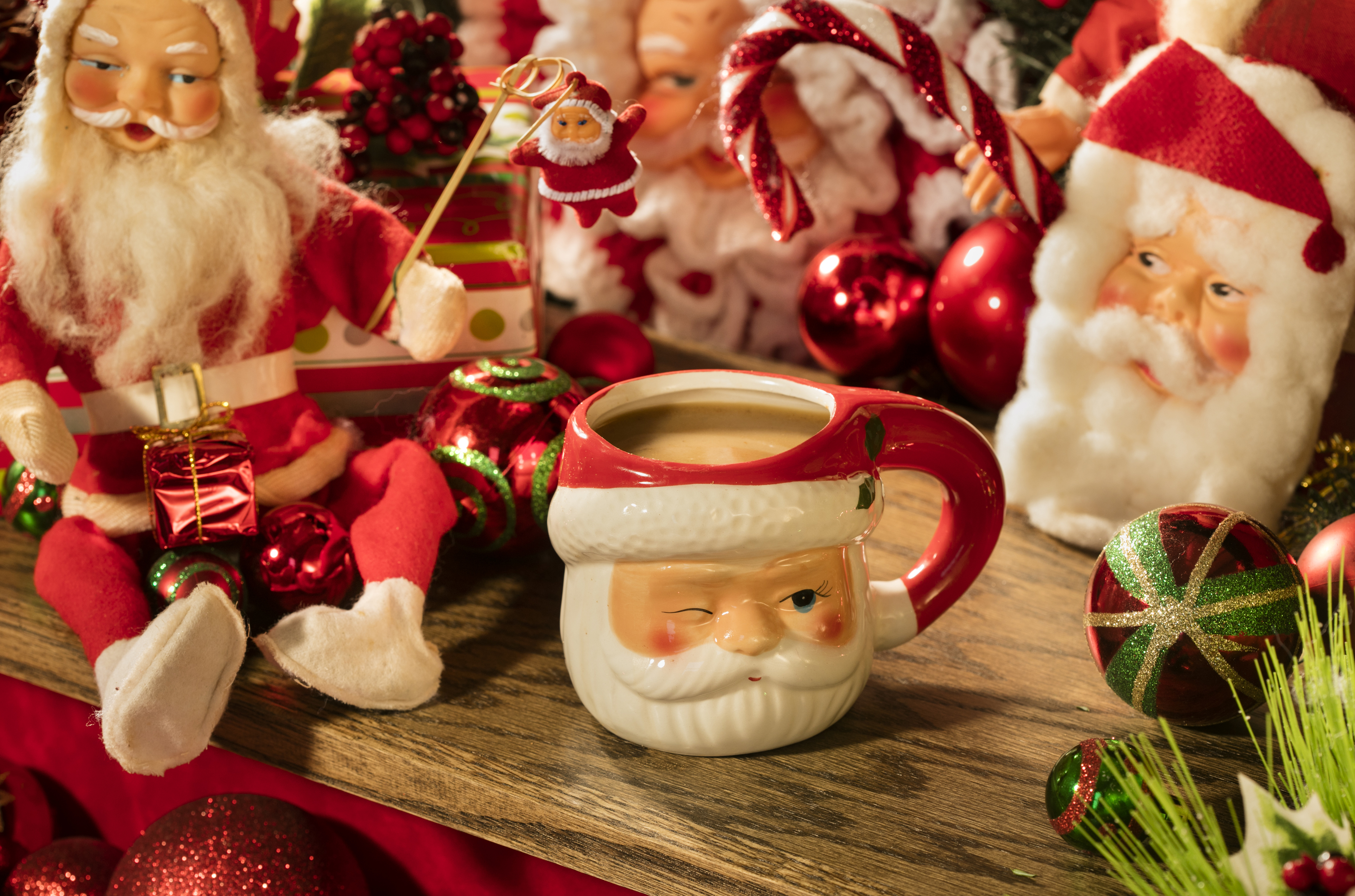 A Santa mug sits on a counter with Santa Claus toys