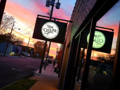 Exterior photo of SBC's The Cellar, with a sunset visible behind the building's sign